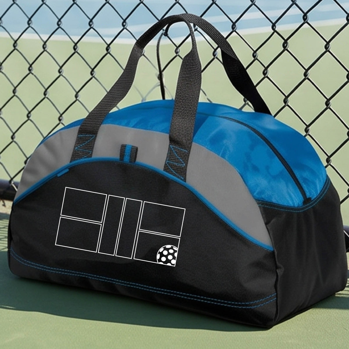 A close up of royal blue, gray and black pickleball duffel bag with a white pickleball court and ball graphic.
