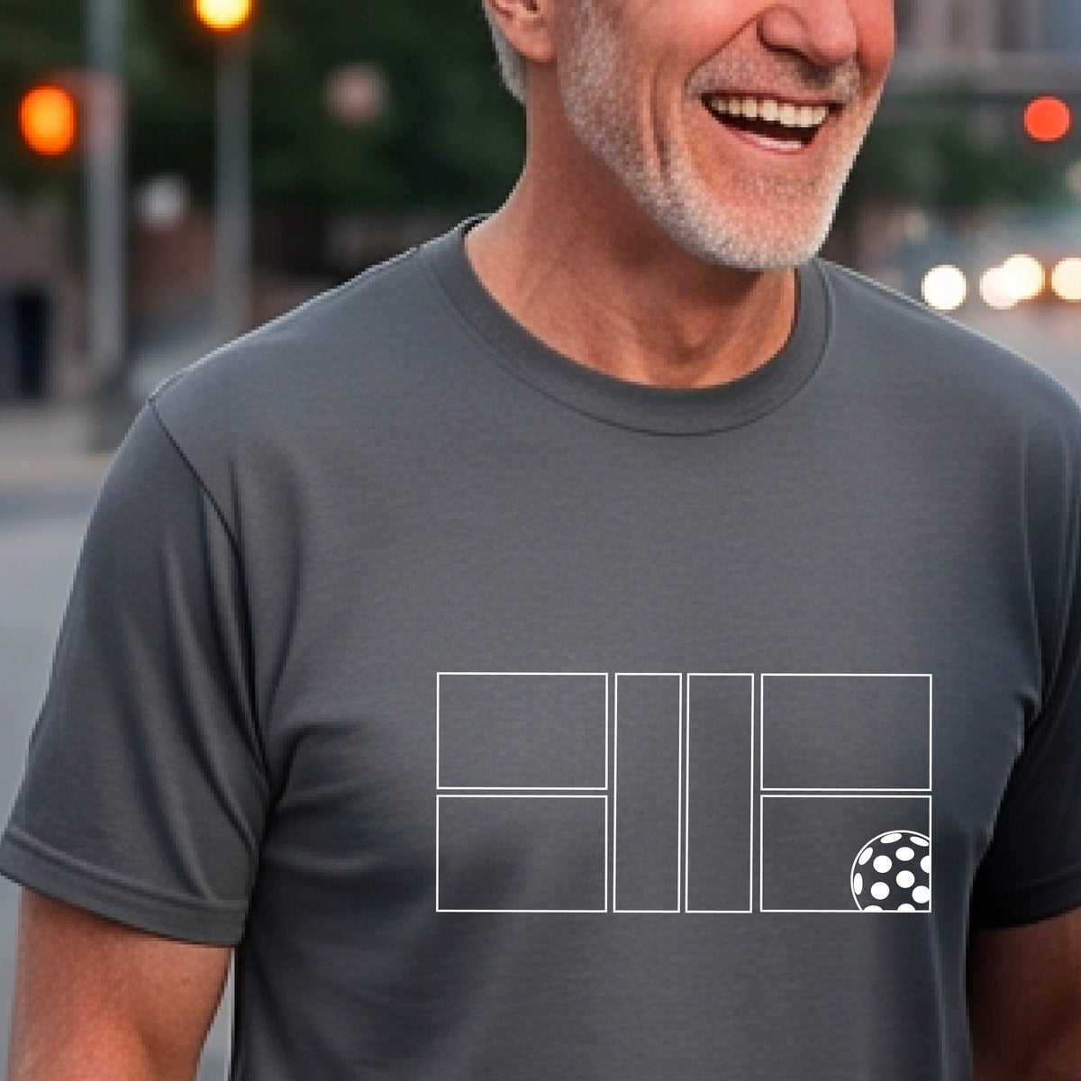 A man wearing a gray short-sleeve shirt with a graphic of a white pickleball court and ball on the front.