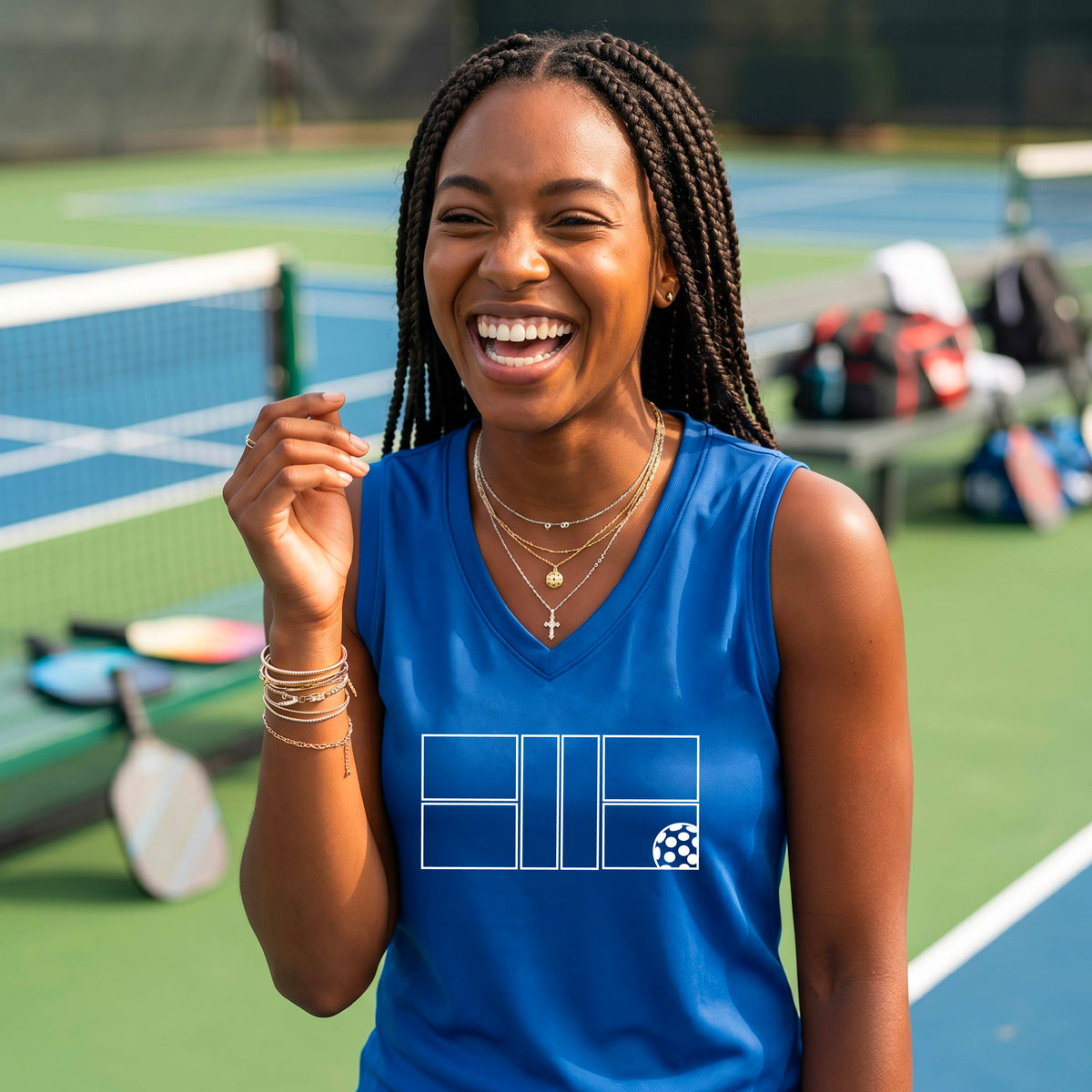 A woman wearing a royal blue sleeveless V-neck athletic tank top with a white pickleball court and ball graphic.