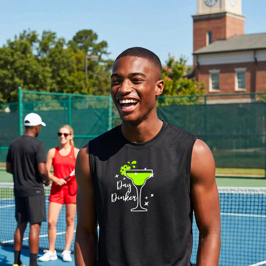 A man smiling on an outdoor pickleball court wearing a black sleeveless tank top with a green cocktail martini glass with a pickleball lim garnish graphic and the words 'Day Dinkster' printed on the front. 