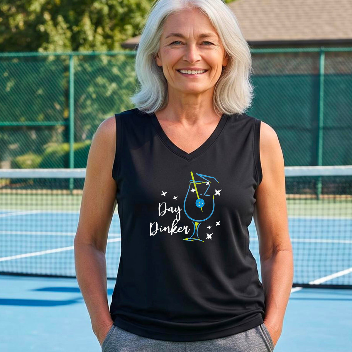 A woman wearing a black sleeveless V-neck athletic tank top with a colorful cocktail martini glass with a pickleball olive garnish"