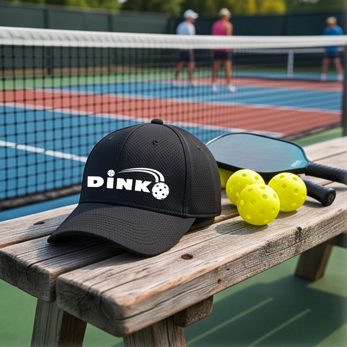A close-up of a black baseball cap with a white 'DINK' logo and pickleball graphic on the front.