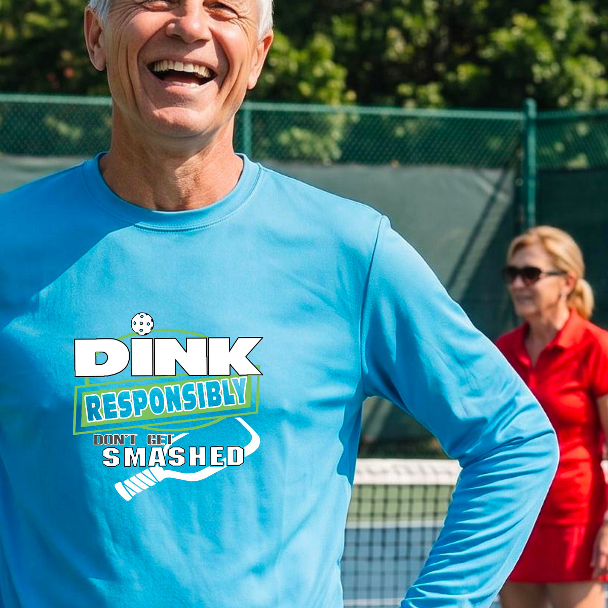 A man wearing a bright blue long-sleeve t-shirt with a 'DINK RESPONSIBLY DON'T LET SMASHED' graphic on the front, and a pickelball paddle graphic.