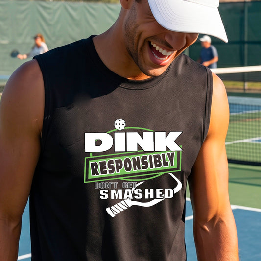 A man on a pickleball court wearing a black sleeveless graphic shirt with the text 'DINK RESPONSIBLY DON'T GET SMASHED' in white and green, along with a white pickleball paddle under the text.
