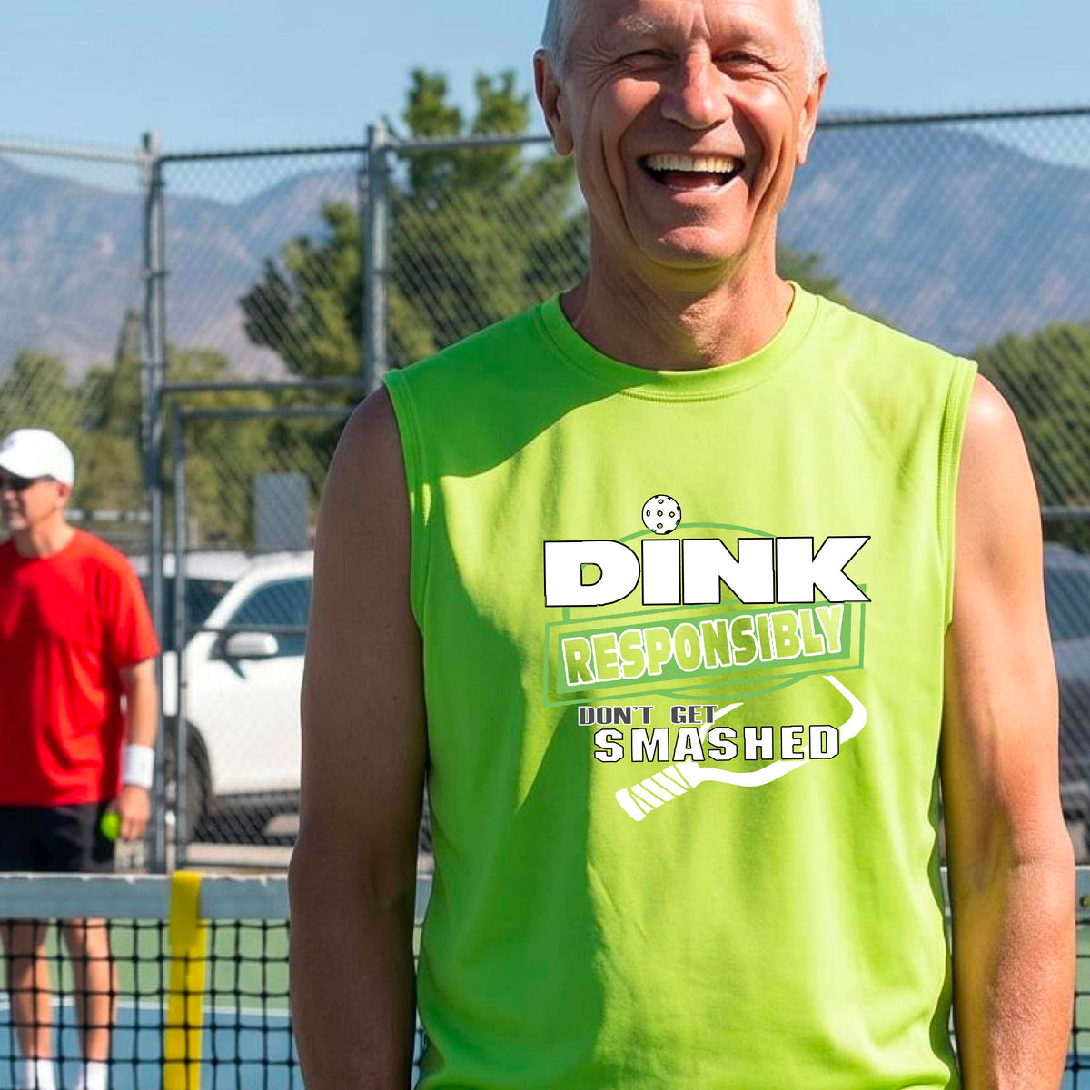 A man on a pickleball court wearing a lime green sleeveless graphic shirt with the text 'DINK RESPONSIBLY DON'T GET SMASHED' in white and green, along with a white pickleball paddle under the text.