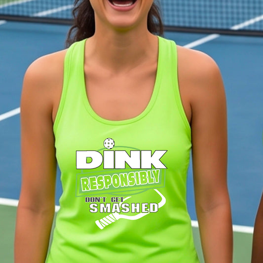 A woman wearing a bright neon green racerback tank top with a white and light green graphic that reads 'DINK RESPONSIBLY DON'T GET SMASHED' with a pickleball paddle graphic. 