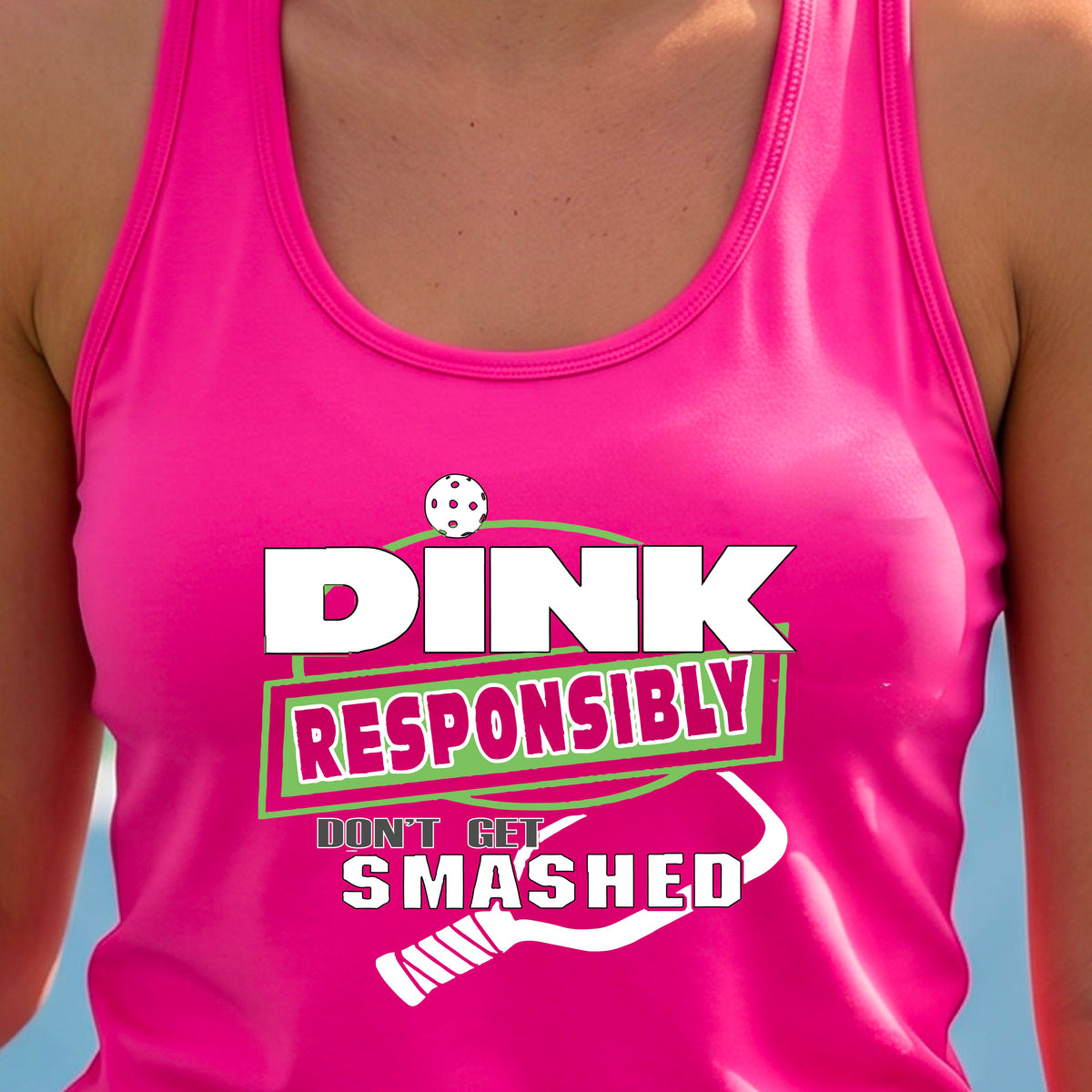 A woman wearing a bright pink racerback tank top with a white and light green graphic that reads 'DINK RESPONSIBLY DON'T GET SMASHED' with a pickleball paddle graphic. 