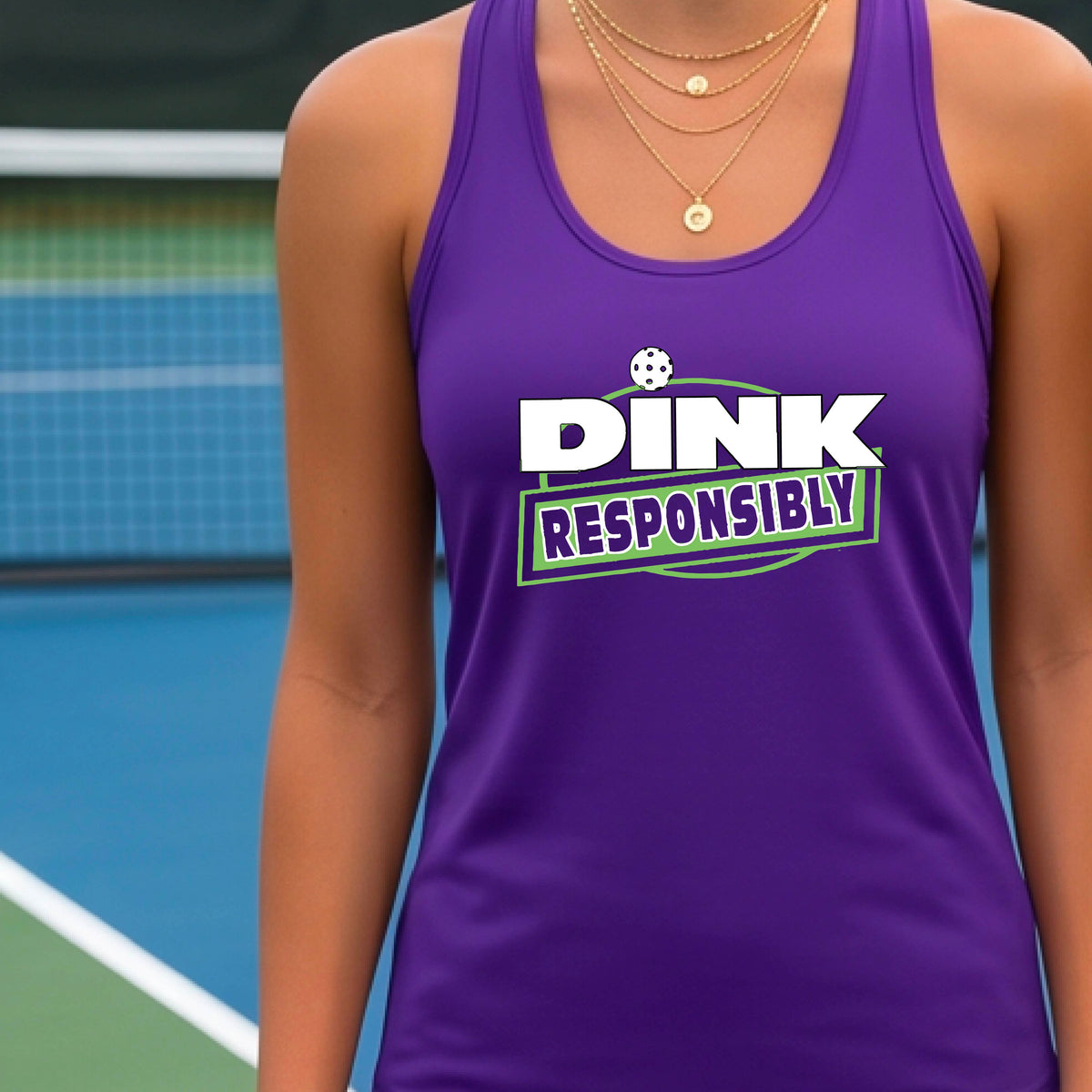 A woman on a pickleball court wearing a purple tank top with a 'DINK RESPONSIBLY' graphic printed on the front.
