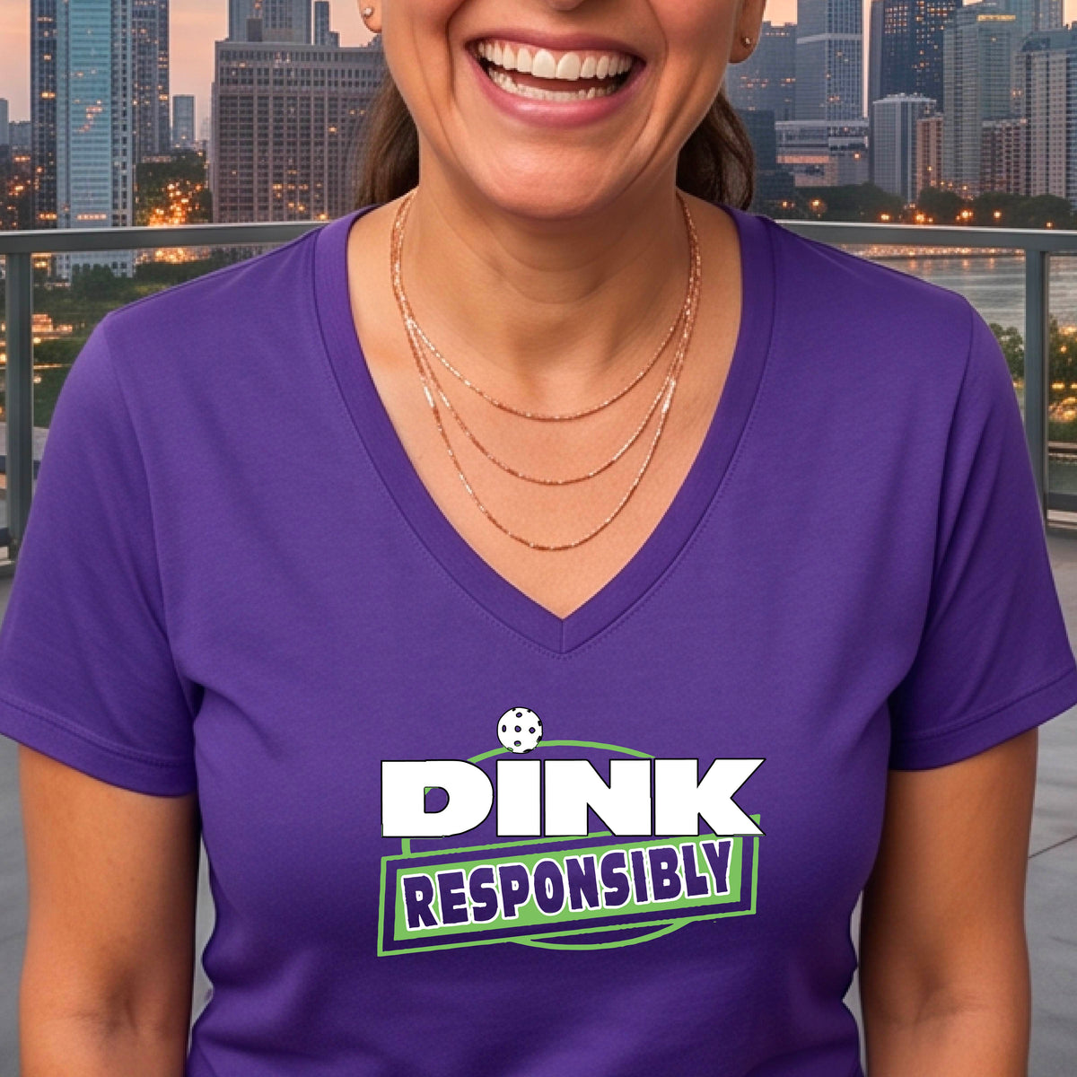 A woman wearing a purple V-neck t-shirt with a pickleball 'DINK RESPONSIBLY' graphic on the ches.