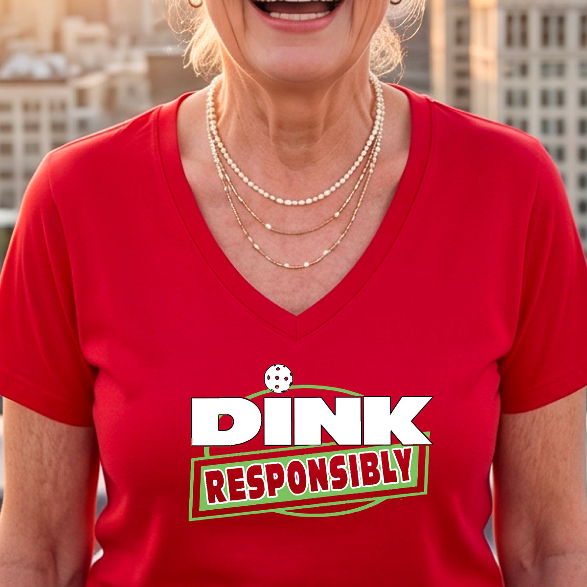 A woman wearing a red V-neck t-shirt with a pickleball 'DINK RESPONSIBLY' graphic on the ches.