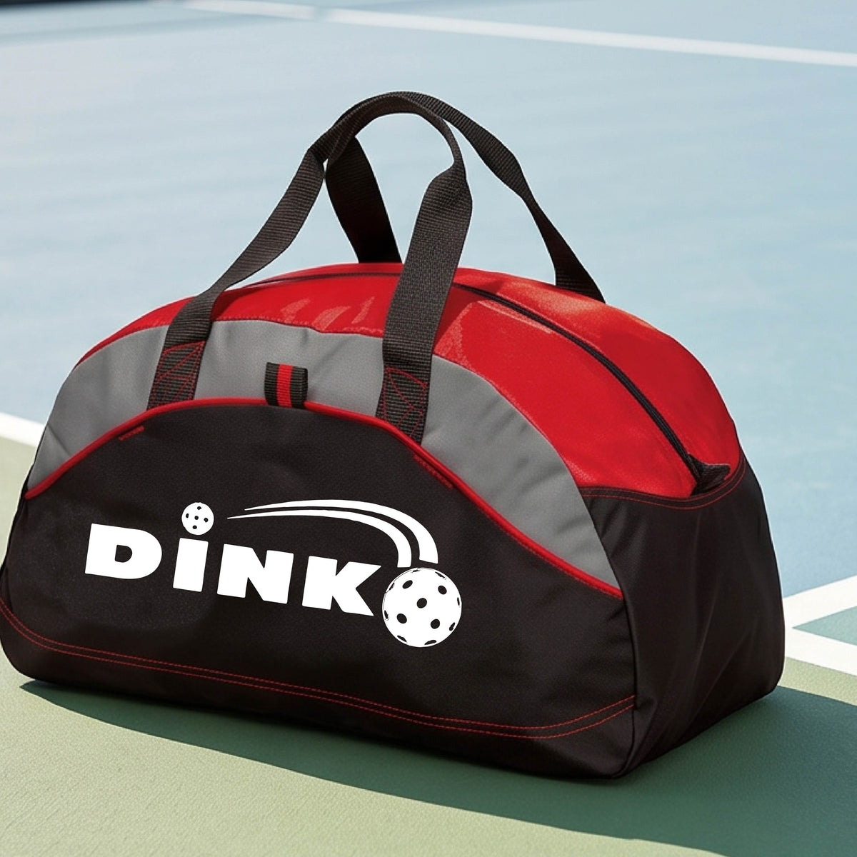 A close up of a red, black and gray pickleball  duffel bag with a pickleball design of text 'DINK' with a white pickleall in flight, on a pickleball court .