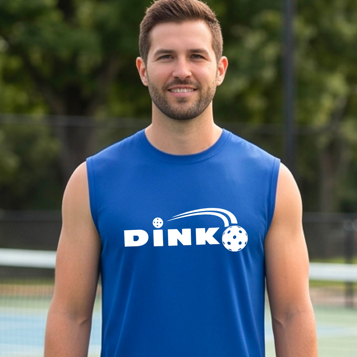 A man wearing a royal blue sleeveless t-shirt with a pickleball design of text 'DINK' with a white pickleall in flight, standing on a pickleball court.