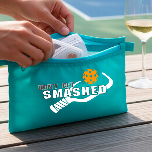 A teal cosmetic toiletry pouch with a white 'DON'T GET SMASHED' graphic including a pickleball paddle and a colorful pickleball graphic. 