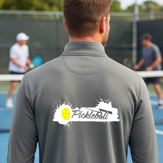 A man viewed from behind wearing a gray long-sleeve quarter-zip athletic shirt with a 'Pickleball' splatter  graphic standing on a pickleball court. 