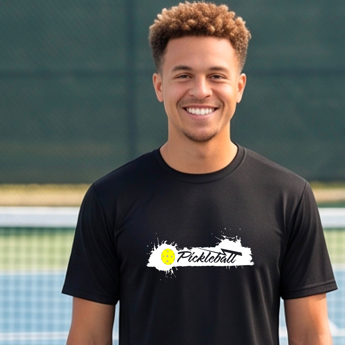 A smiling man wearing a black t-shirt with a 'Pickleball' splatter graphic on the chest, 