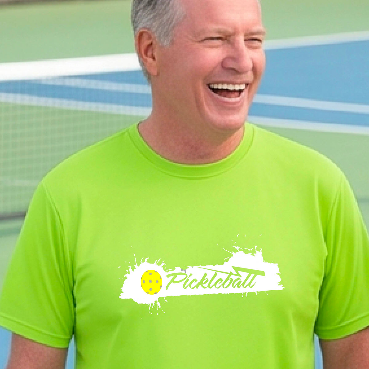 A smiling man wearing a lime green t-shirt with a 'Pickleball' splatter graphic on the chest, 