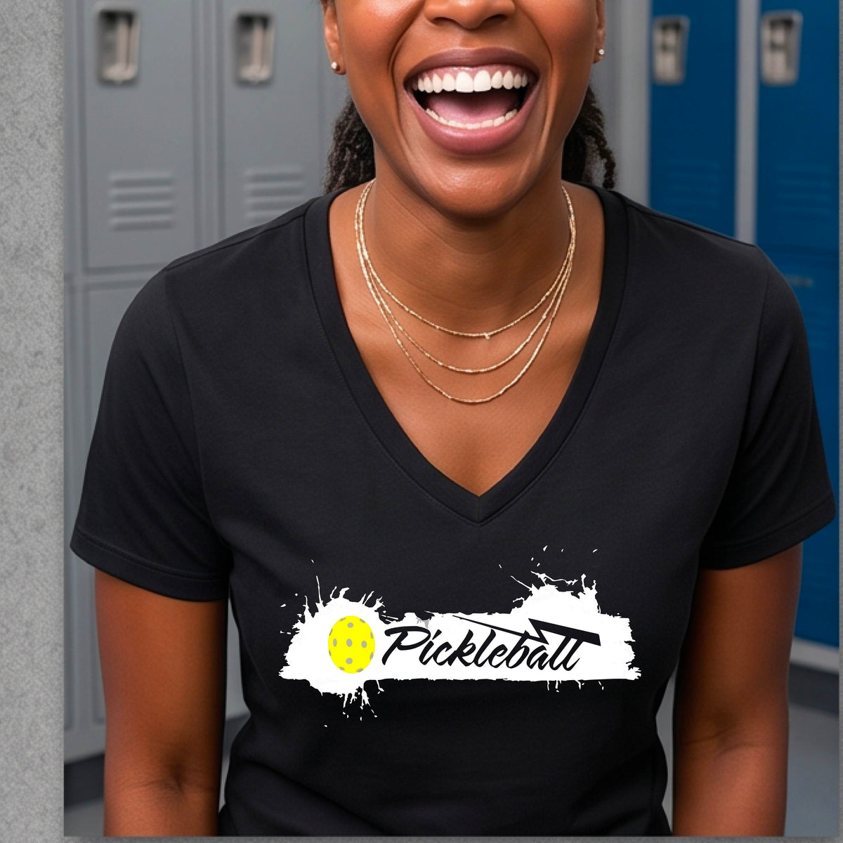 A woman wearing a black V-neck t-shirt with a white and yellow 'Pickleball' splatter graphic on the front..