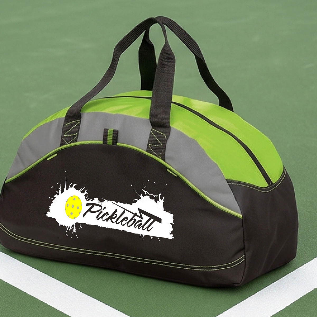 A lime green,  black and gray pickleball duffel bag with a white and yellow 'Pickleball' splatter graphic, resting on a pickleball court.