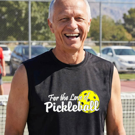 A close-up of a man wearing a black sleeveless t-shirt with a pickleball graphic on the left bottom left of ‘FOR THE LOVE OF PICKLEBALL’ in white with a yellow pickleball behind it.  