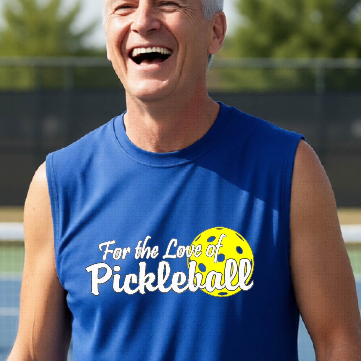 A close-up of a man wearing a royal blue sleeveless t-shirt with a pickleball graphic on the left bottom left of ‘FOR THE LOVE OF PICKLEBALL’ in white with a yellow pickleball behind it.  