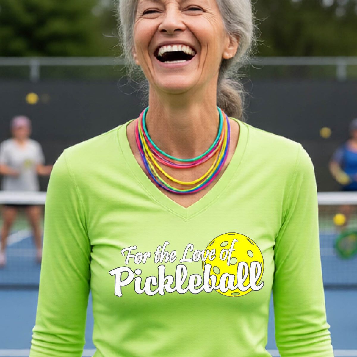 A close-up of a womens lime green long-sleeve v-neck t-shirt with a pickleball graphic of ‘FOR THE LOVE OF PICKLEBALL’ in white with a yellow pickleball behind it graphic on the front.