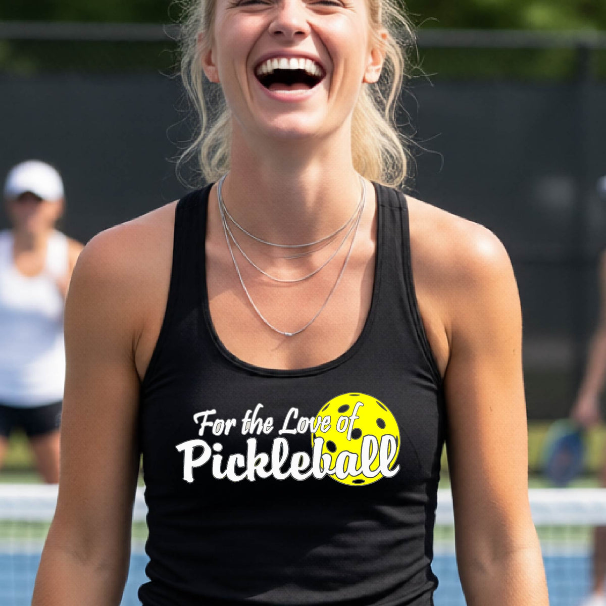 A close-up of a black womens racerback tank with a pickleball graphic of ‘FOR THE LOVE OF PICKLEBALL’ in white with a yellow pickleball behind it graphic on the front.