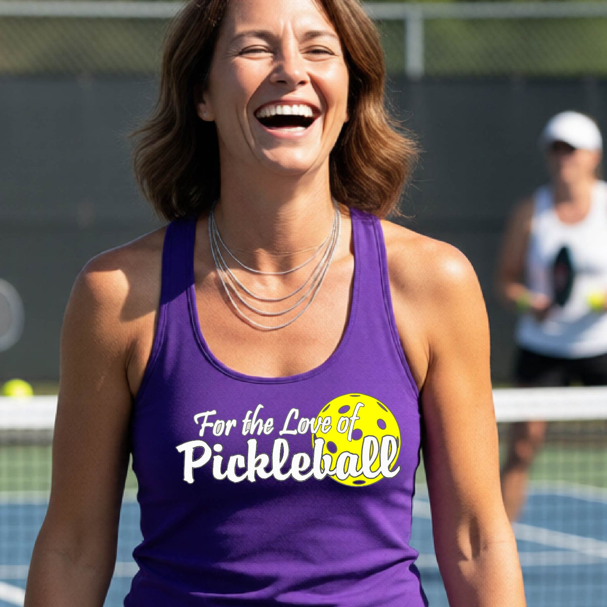 A close-up of a purple womens racerback tank with a pickleball graphic of ‘FOR THE LOVE OF PICKLEBALL’ in white with a yellow pickleball behind it graphic on the front.