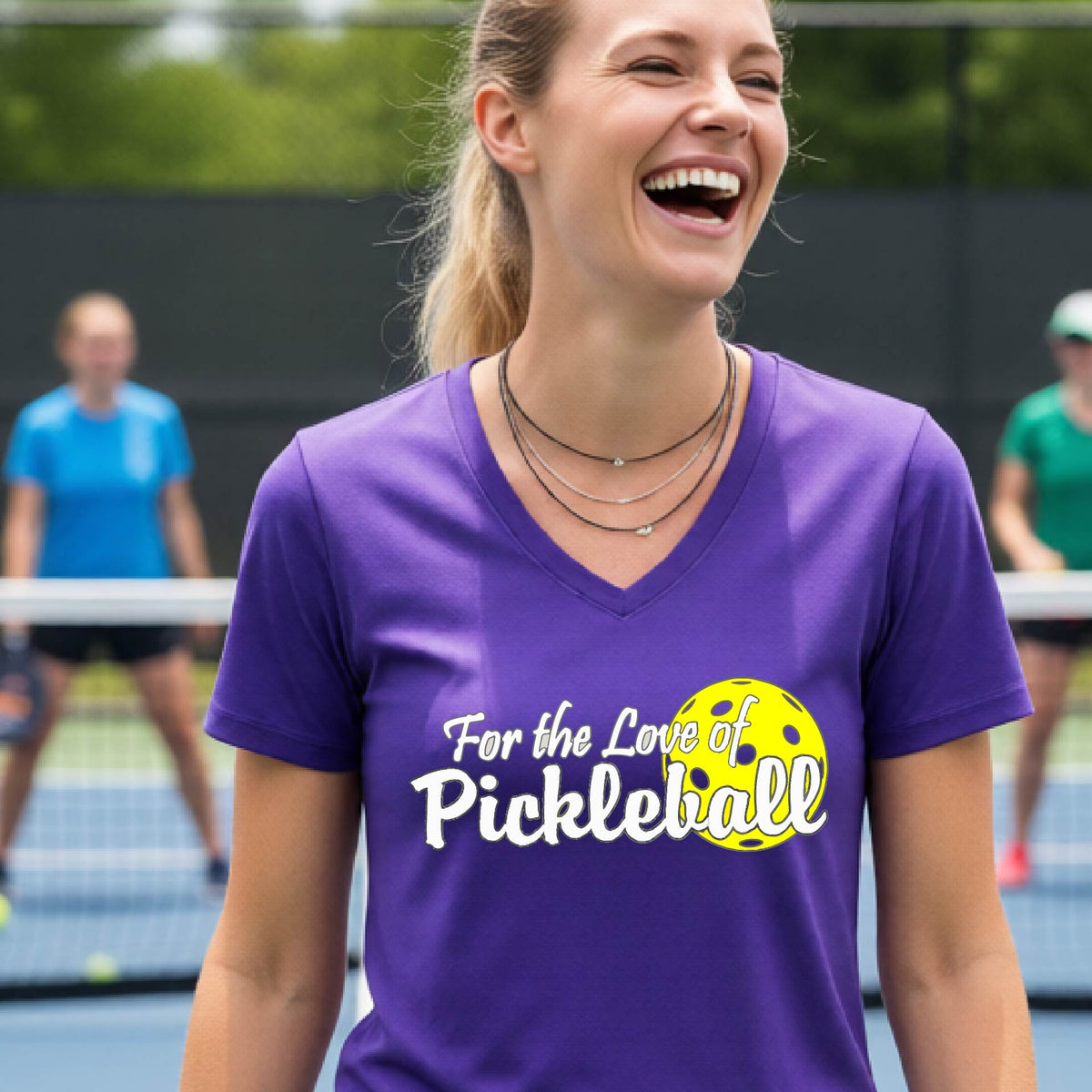 A close-up of a womens purple short-sleeve v-neck t-shirt with a pickleball graphic of ‘FOR THE LOVE OF PICKLEBALL’ in white with a yellow pickleball behind it graphic on the front.