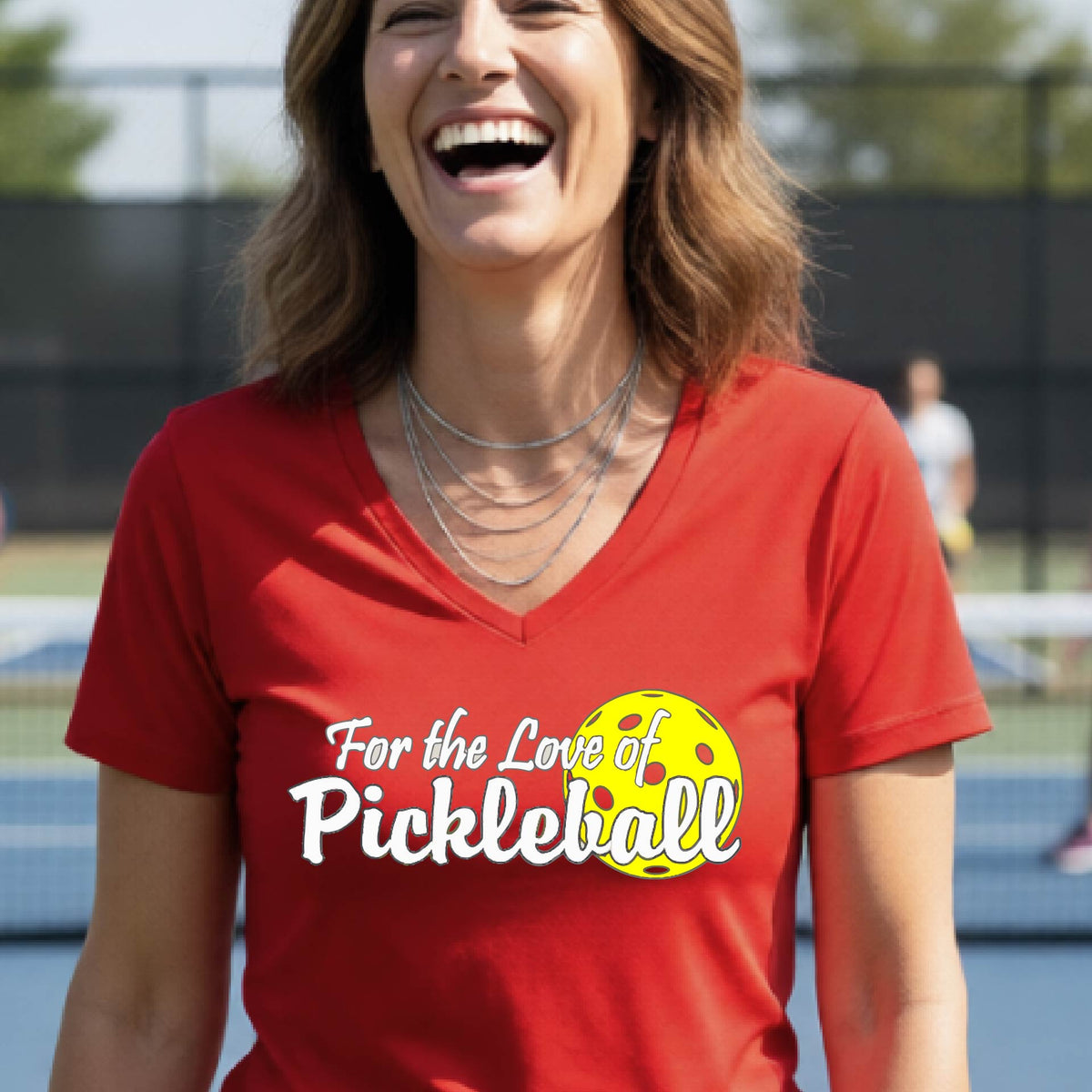 A close-up of a womens red short-sleeve v-neck t-shirt with a pickleball graphic of ‘FOR THE LOVE OF PICKLEBALL’ in white with a yellow pickleball behind it graphic on the front.