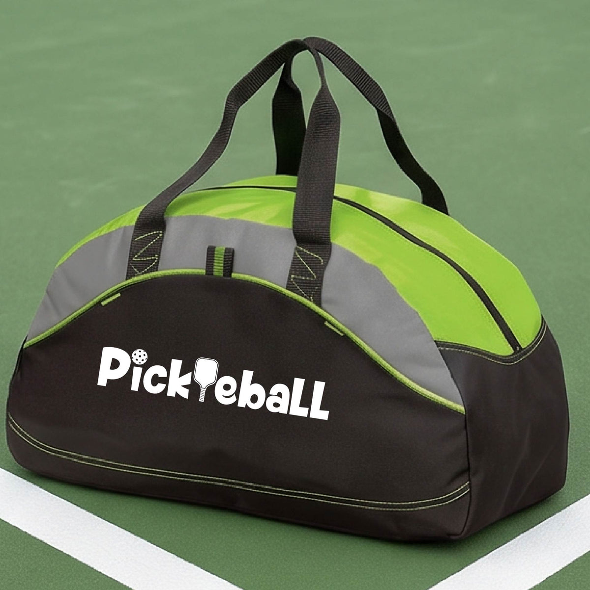 A close-up of a medium-size lime green, gray and black duffel bag with a white graphic text 'PICKLEBALL' on the leg with a pickleball paddle replacing the L, on a pickleball court.