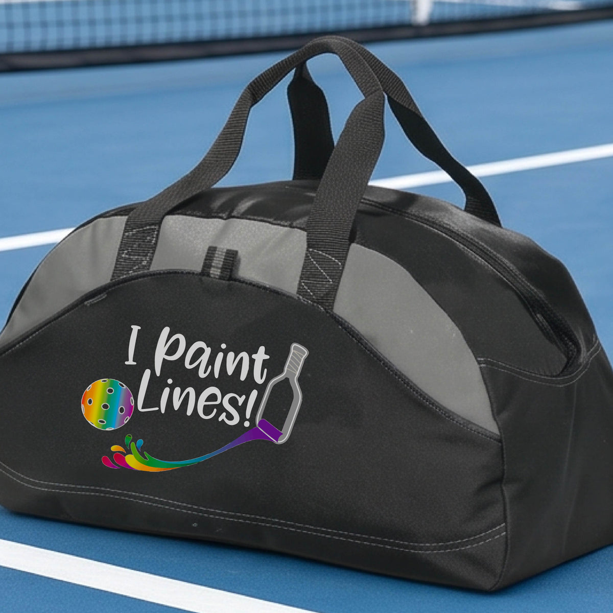 A close-up of gray and black medium size duffel bag with a graphic on the front that has white text "I PAINT LINES'  with a white pickleball paddle painting multi-colored lines leading a mutli-colored pickleball.
