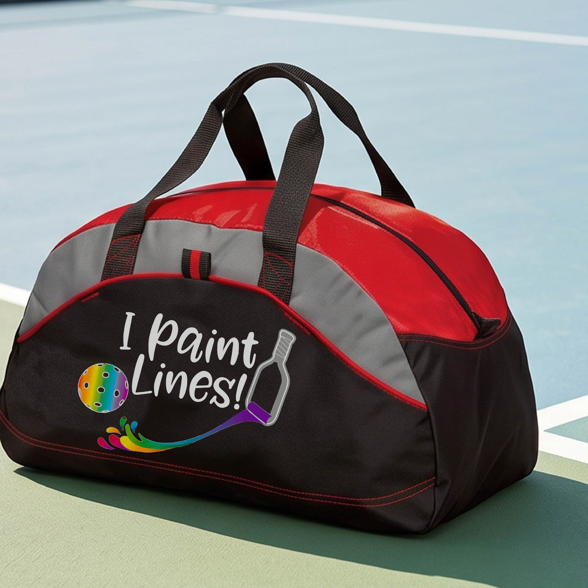 A close-up of red, gray and black medium size duffel bag with a graphic on the front that has white text "I PAINT LINES'  with a white pickleball paddle painting multi-colored lines leading a mutli-colored pickleball.