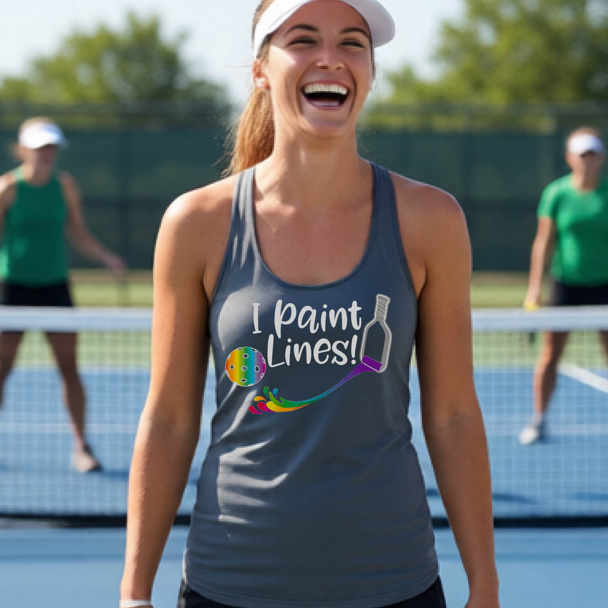 A close-up of a woman wearing a gray racerback tank top with a graphic on the front that has white text "I PAINT LINES'  with a white pickleball paddle painting multi-colored lines leading a mutli-colored pickleball.