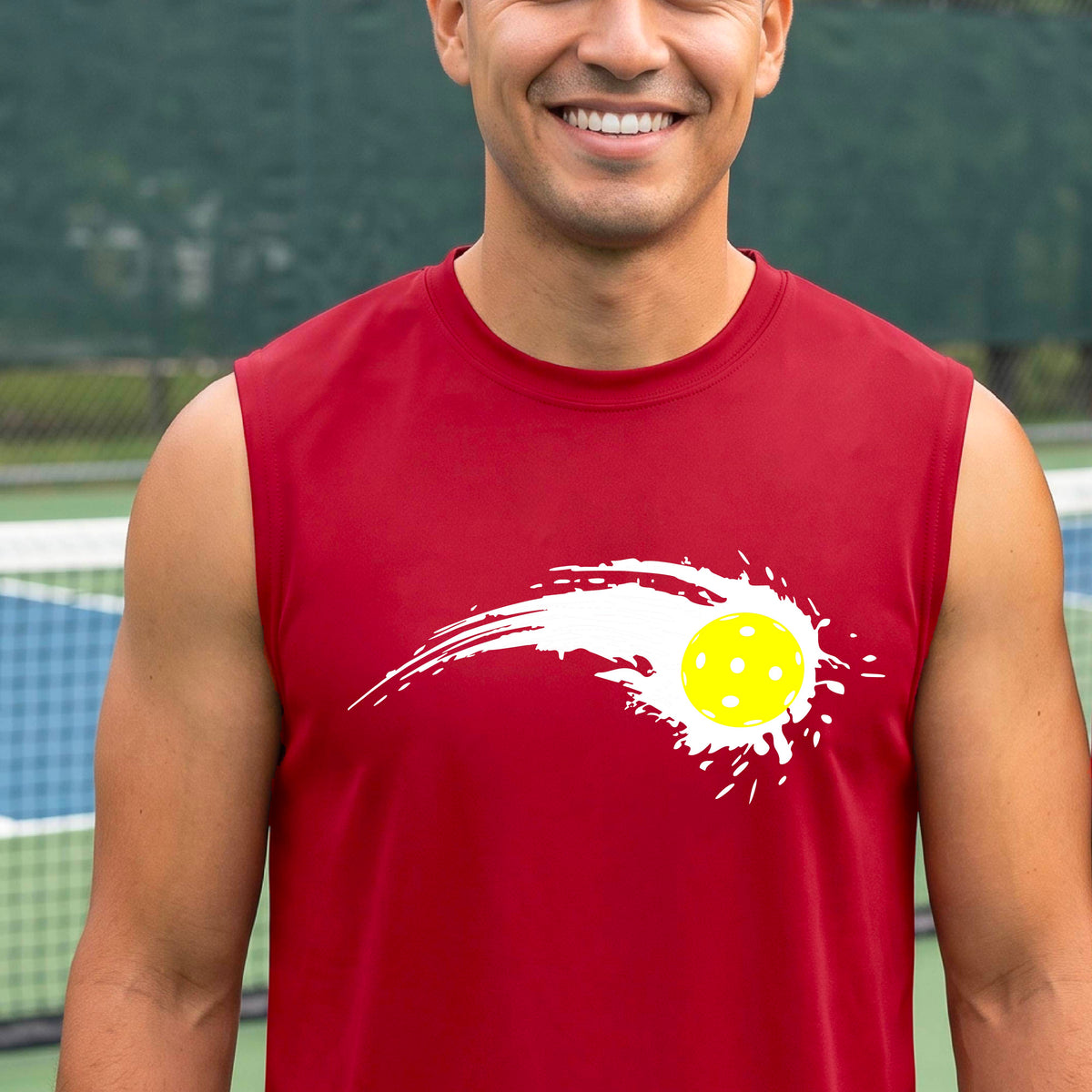 A man wearing a red sleeveless T-shirt with a white pickleball graphic of a yellow pickleball with a motion trail effect, displayed in front of a pickleball court. 