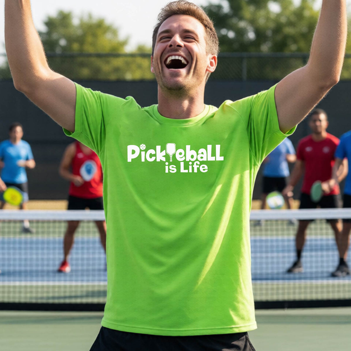 A man on a pickleball court wearing a bright lime green t-shirt with the text 'Pickleball is Life' in white, with a pickleball paddle in place of the first L.