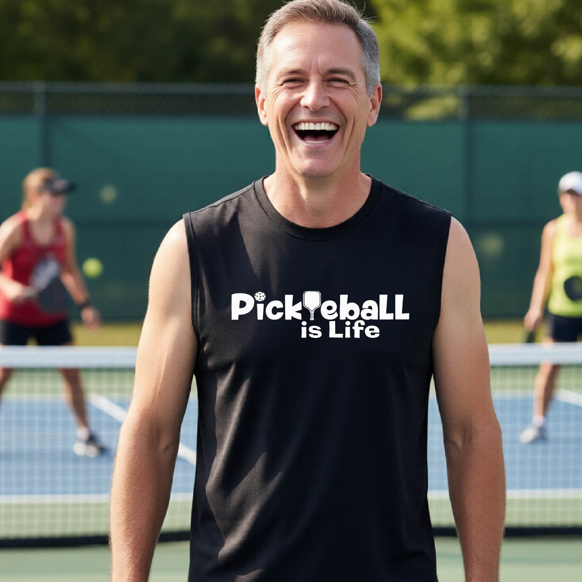 A smiling man on a pickleball court wearing a black sleeveless shirt with the text 'PickYeball is Life' in white.