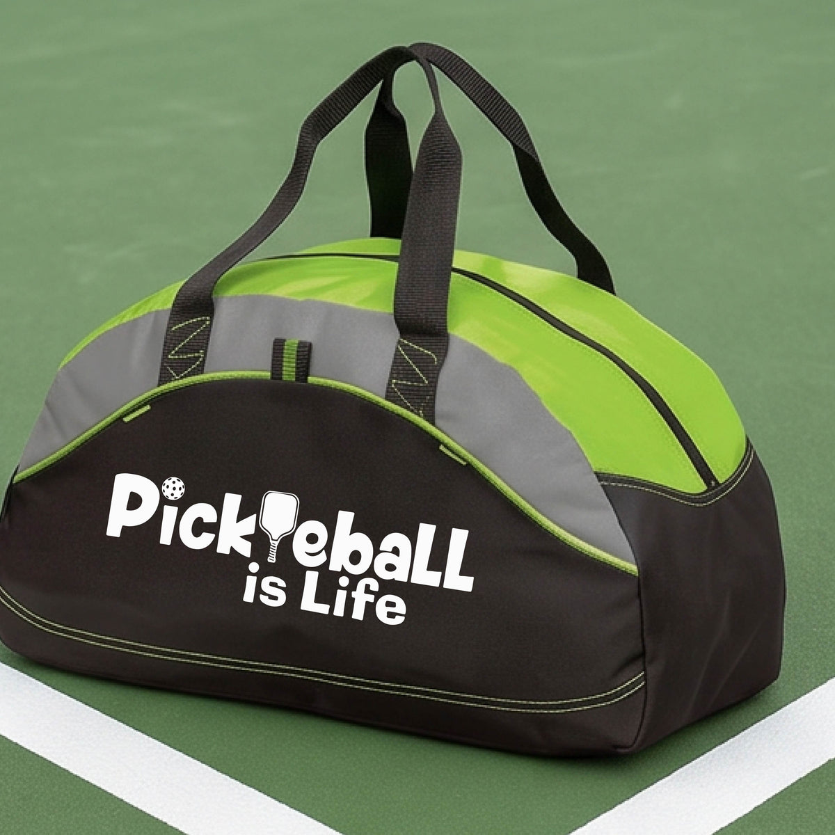 A lime green, black, and gray duffel bag with the text 'Pickbeall is Life' printed on the front, placed on a tennis court.