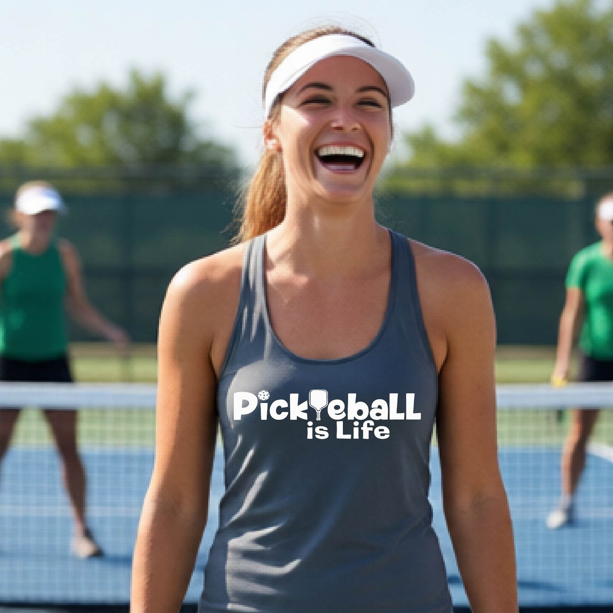 A woman wearing a gray racerback tank top with the slogan 'Pickleball is Life' printed in white across the back, with a pickleball paddle replacing the L. 