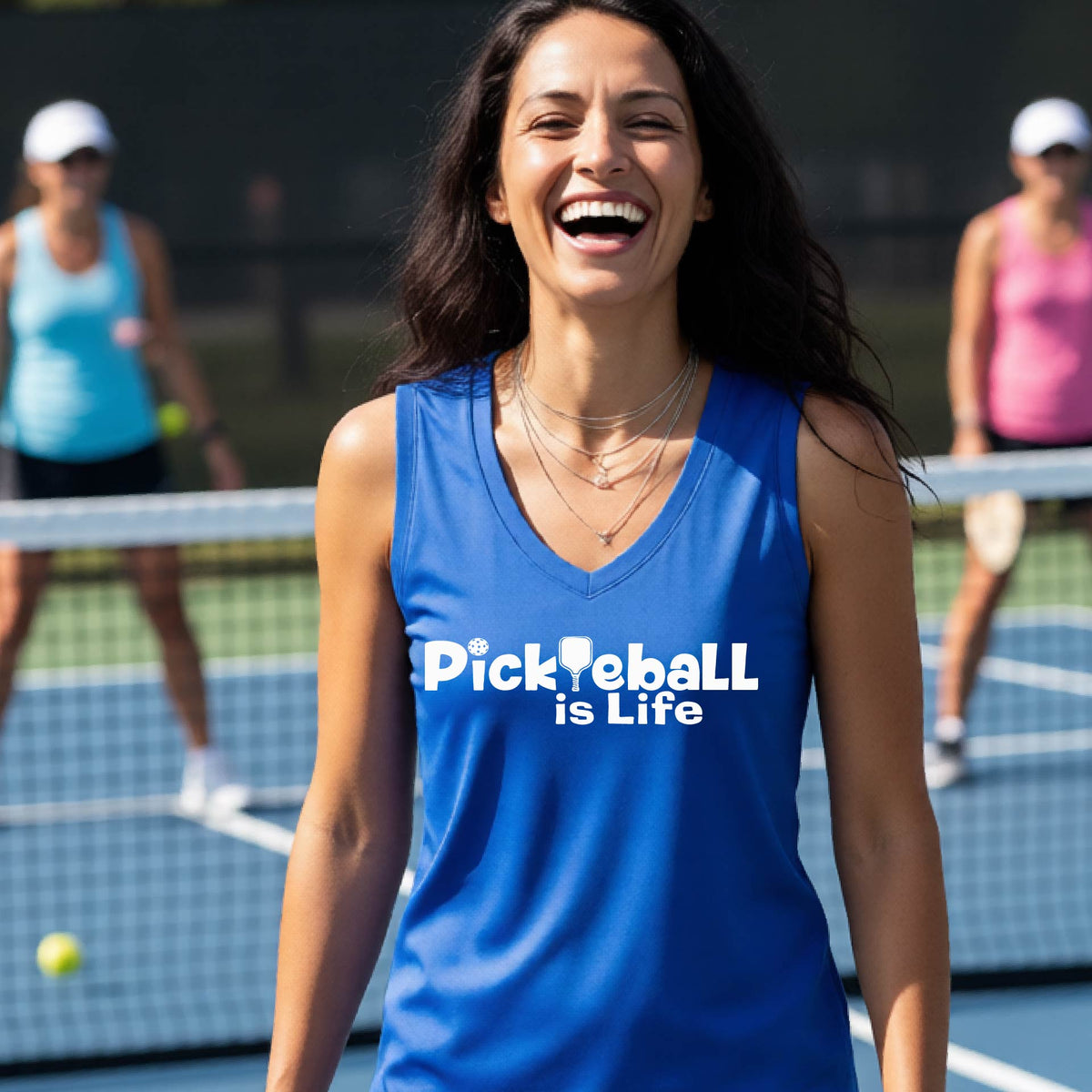 A woman wearing a royal blue sleeveless v-neck t-shirt with the slogan 'Pickleball is Life' printed in white across the back, with a pickleball paddle replacing the L.