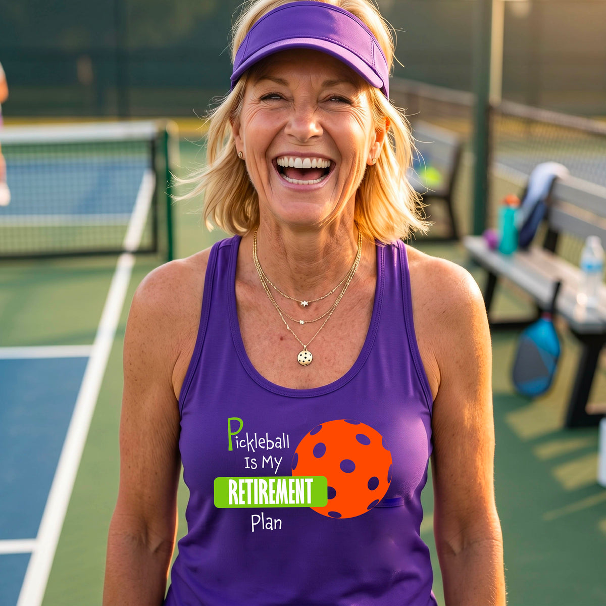 A smiling woman on a pickleball court wearing a purple tank top with the text 'Pickleball is My Retirement Plan' and an orange pickleball graphic.