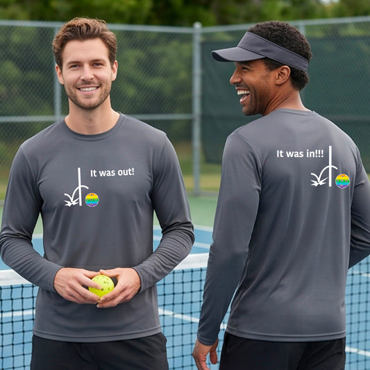 Two men showing a gray long-sleeve t-shirt with a white design of ‘IT WAS OUT!’ and a colorful pickleball on the front, and the back design with a white ‘IT WAS IN!!!’ and a colorful pickleball, standing on a pickleball court.
