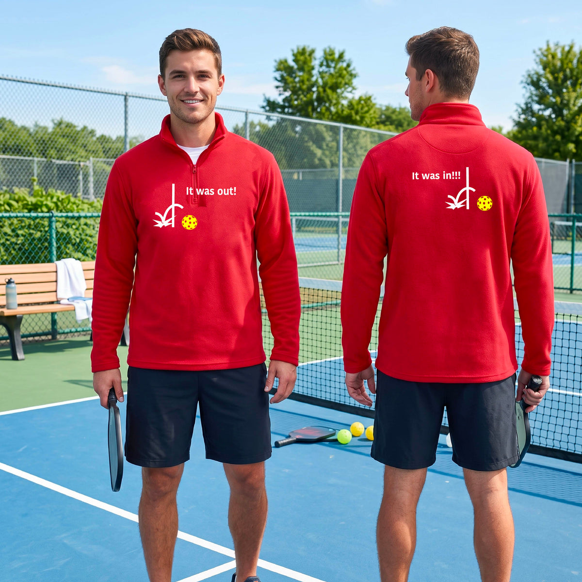 Two men wearing a red quarter-zip shirt with a white design of ‘IT WAS OUT!’ and a colorful pickleball on the front, and the back design with a white ‘IT WAS IN!!!’ and a colorful pickleball, standing on a pickleball court.