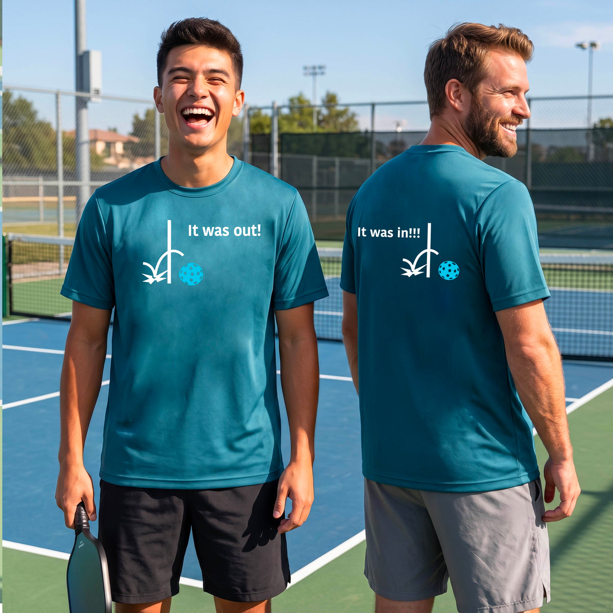Two men showing a teal short-sleeve t-shirt with a white design of ‘IT WAS OUT!’ and a colorful pickleball on the front, and the back design with a white ‘IT WAS IN!!!’ and a colorful pickleball, standing on a pickleball court. 