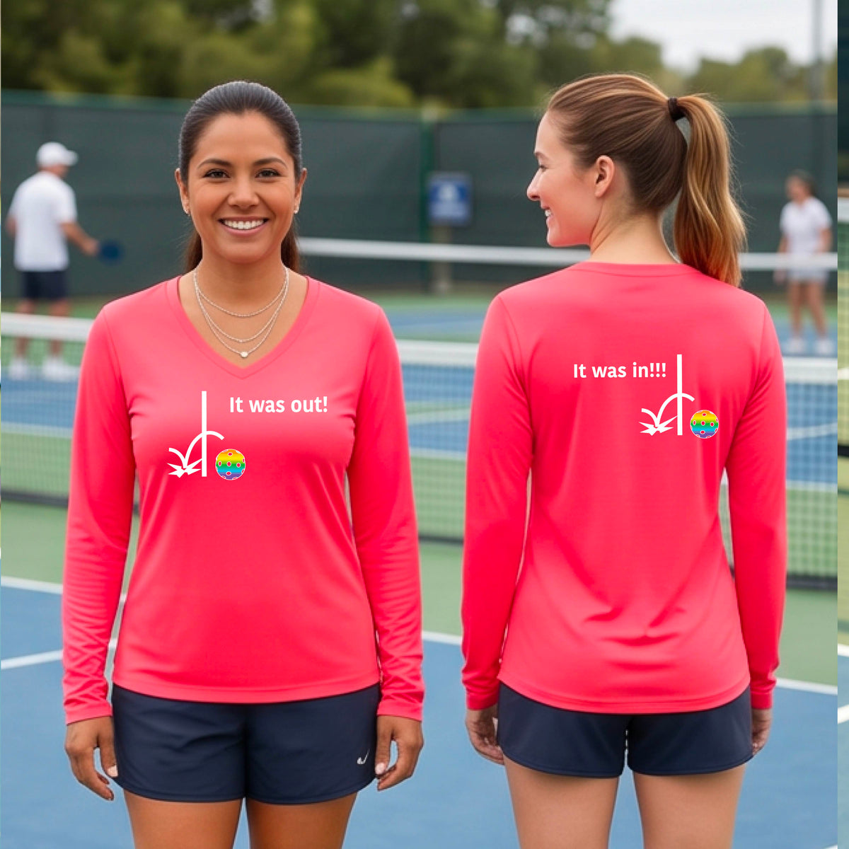Two women wearing a coral pink  long-sleeve t-shirt with a white design of ‘IT WAS OUT!’ and a colorful pickleball on the front, and the back design with a white ‘IT WAS IN!!!’ and a colorful pickleball, standing on a pickleball court.