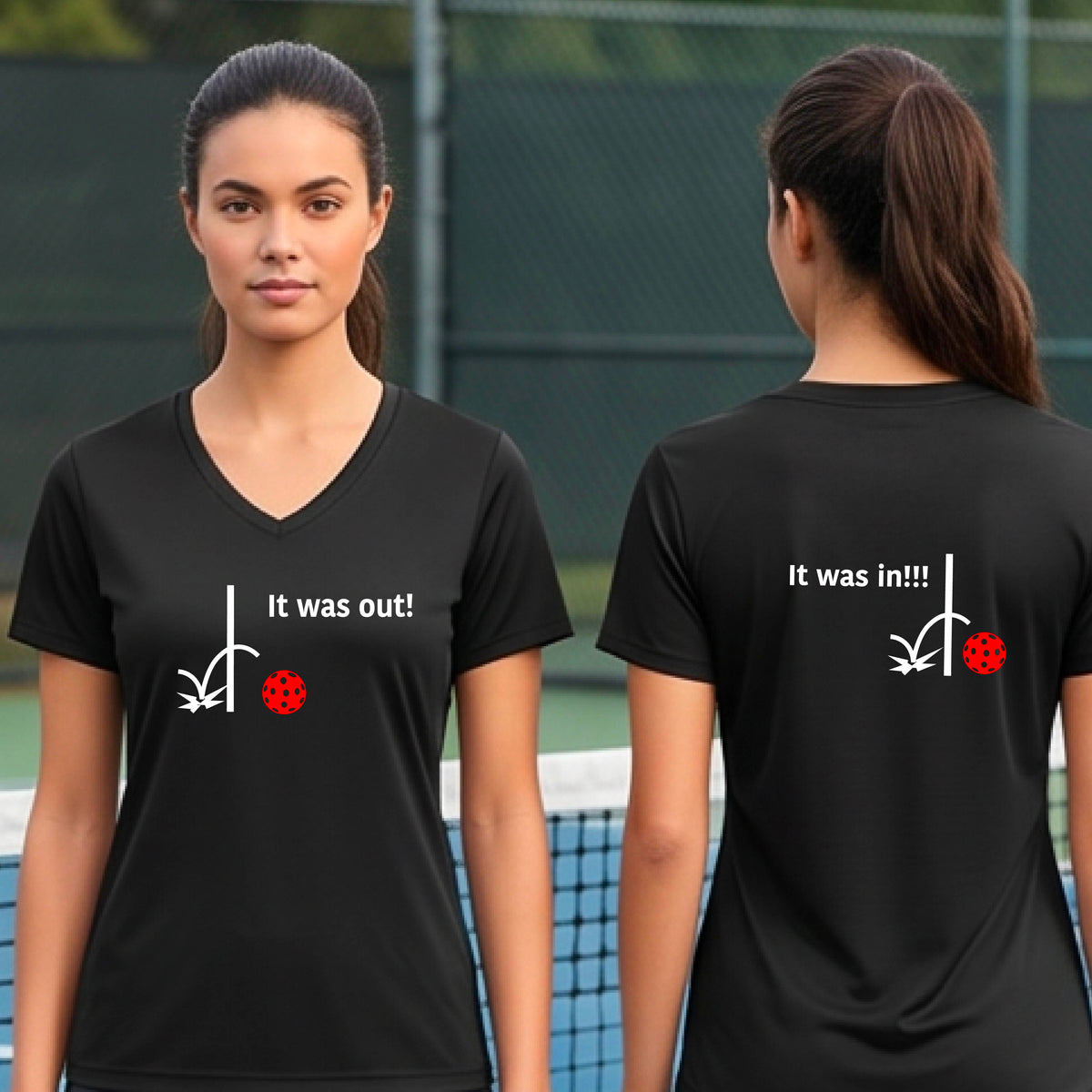 Two women showing a black short-sleeve t-shirt with a white design of ‘IT WAS OUT!’ and a colorful pickleball on the front, and the back design with a white ‘IT WAS IN!!!’ and a colorful pickleball, standing on a pickleball court.