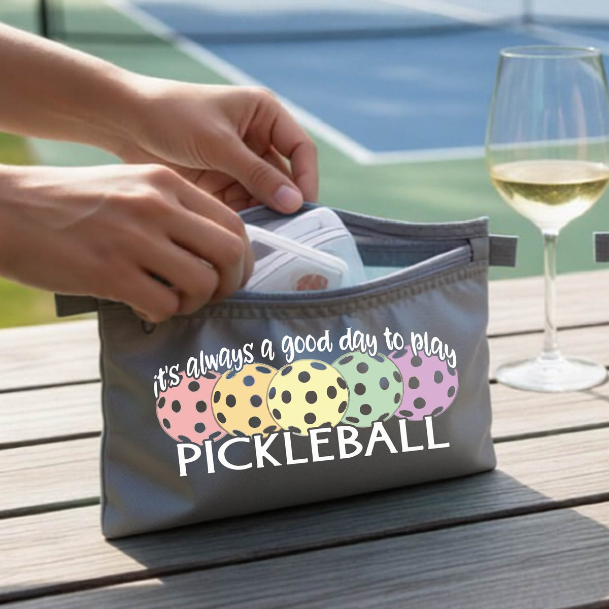 A gray polyester pickleball bag and a graphic of colorful  pickleballs and the text 'it's always a good day to play PICKLEBALL'.