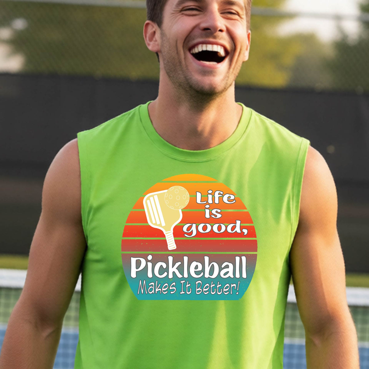 A man wearing a lime green sleeveless t-shirt with a retro multi-colored circle with a pickleball paddle and ball, with white text that says 'LIFE IS GOOD PICKLEBALL MAKES IT BETTER', standing in front of a pickleball court.
