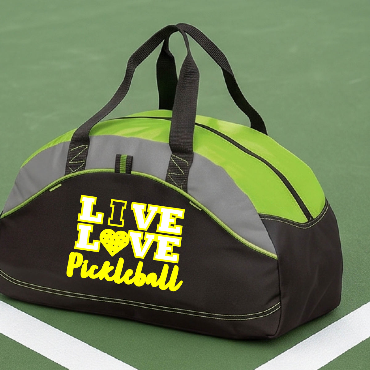A black and lime green pickleball duffel bag with 'LIVE LOVE Pickleball' printed in yellow on the front, resting on a green pickleball court.