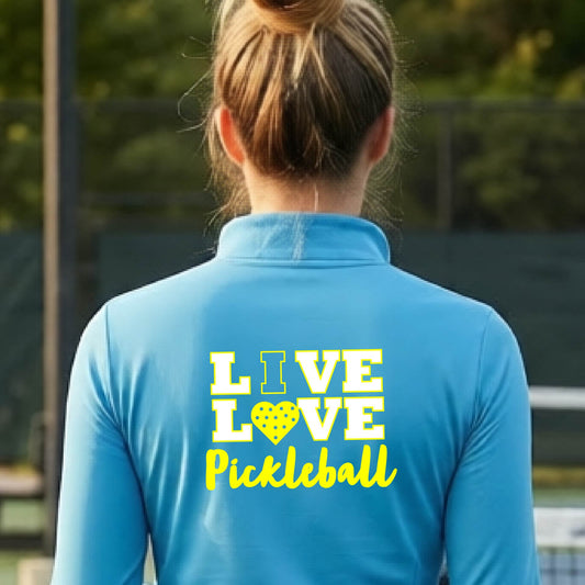 A woman viewed from behind wearing a bright blue quarter-zip athletic pullover with a yellow and white graphic on the back that reads 'LIVE LOVE Pickleball'.