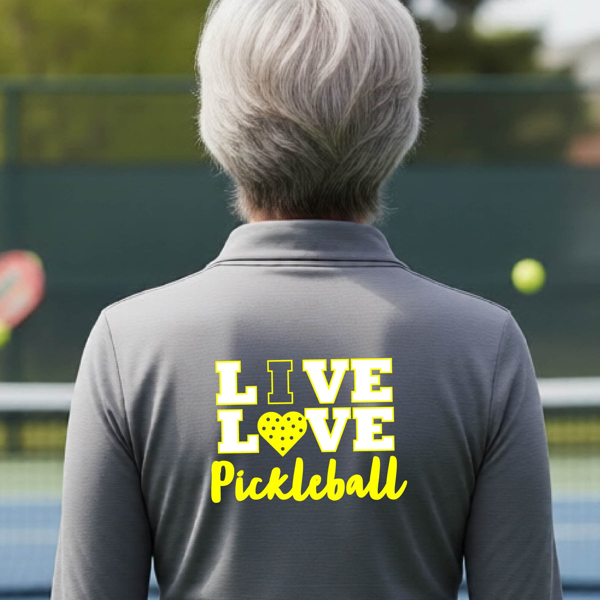 A woman viewed from behind wearing a gray quarter-zip athletic pullover with a yellow and white graphic on the back that reads 'LIVE LOVE Pickleball'.